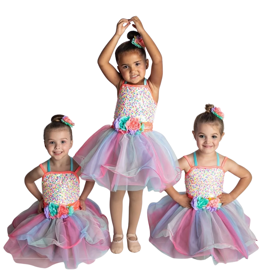 Three preschool ballet dancers wearing colorful tutu costumes posing in studio.